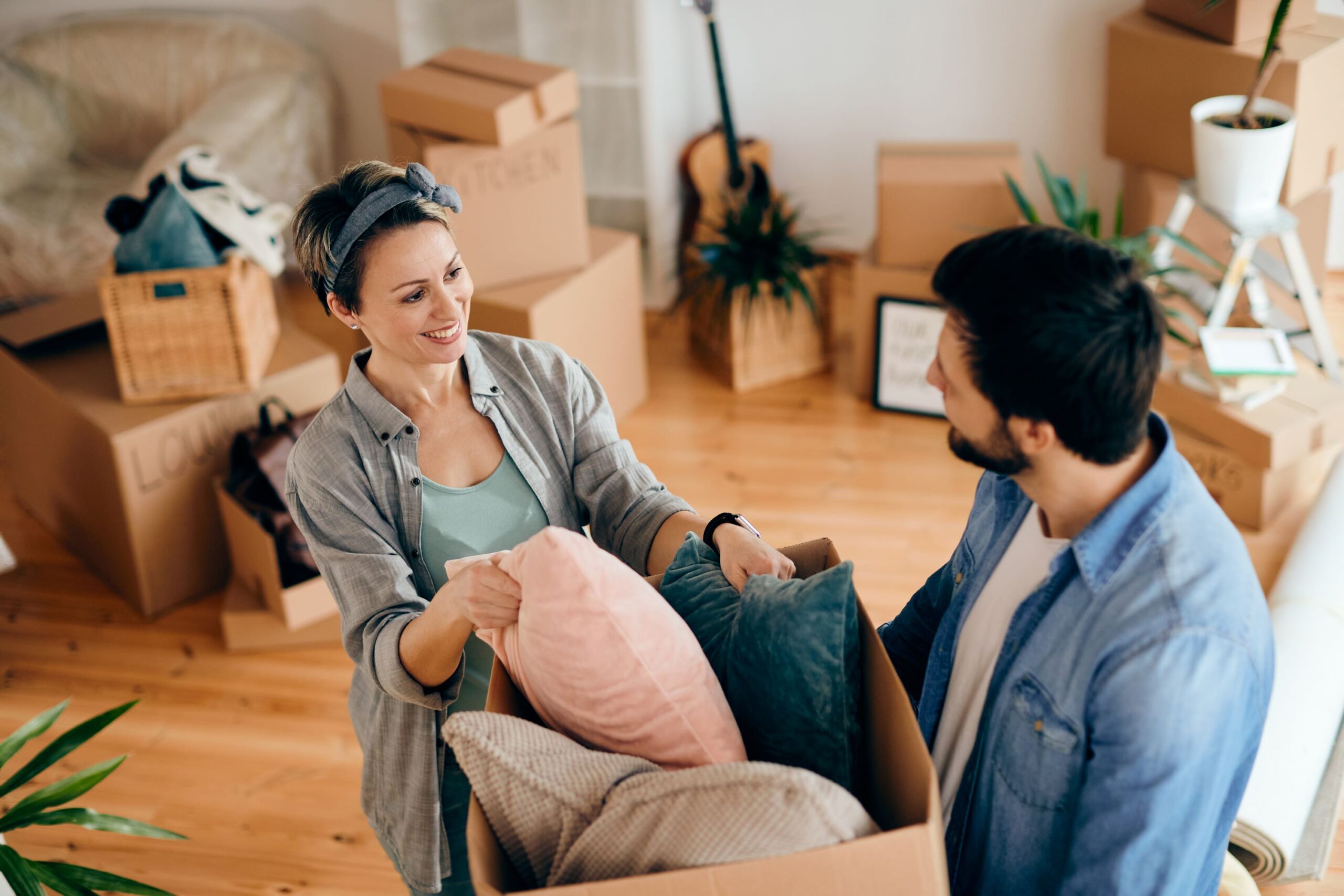 Smiling Couple Unpacking Pillows from The Paper Cardboard in Their New Apartment