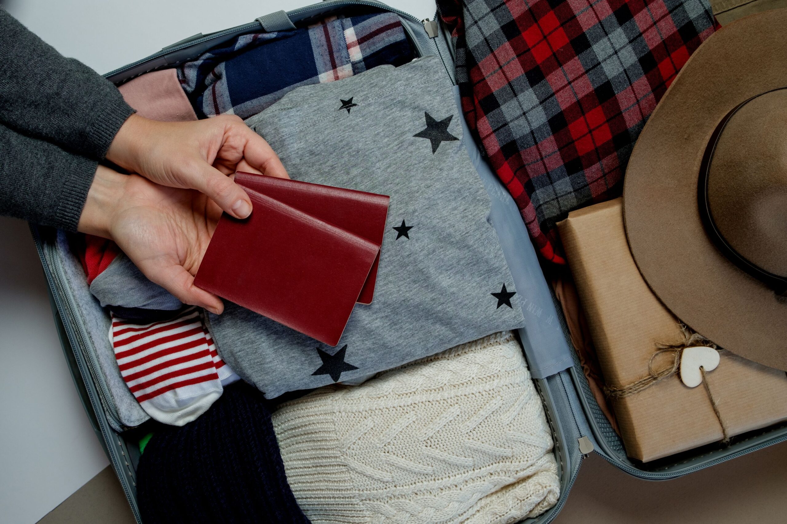 Travel Case Packed With Clothes and a Hand Showing Two Red Passports