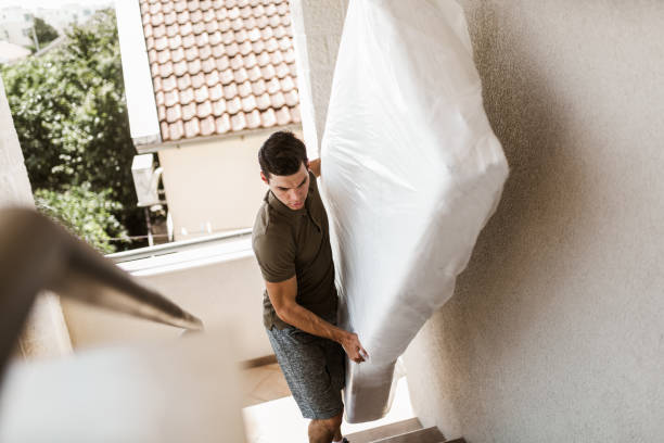 Man Carrying the Mattress While Moving Downward the Staircase