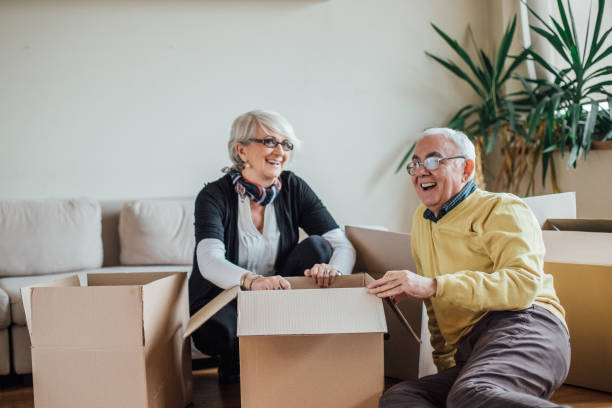 Senior Couple Smiling And Unpacking Paper Containers in Their New Apartment