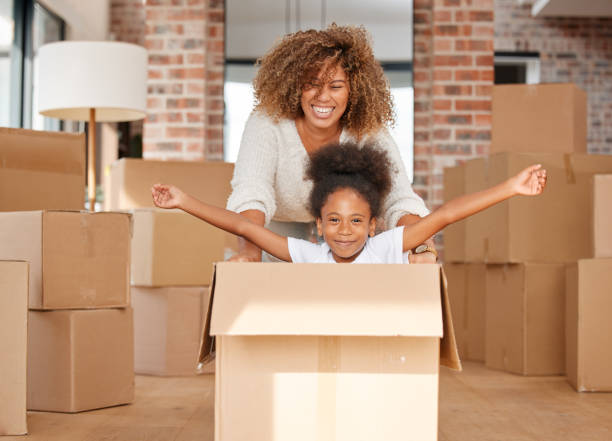 Happy Mother Smiling Behind Her Daughter While Playing in Paper Cardboard Box